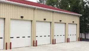 The exterior of a commercial building with several Clopay white sectional garage doors featuring windows.