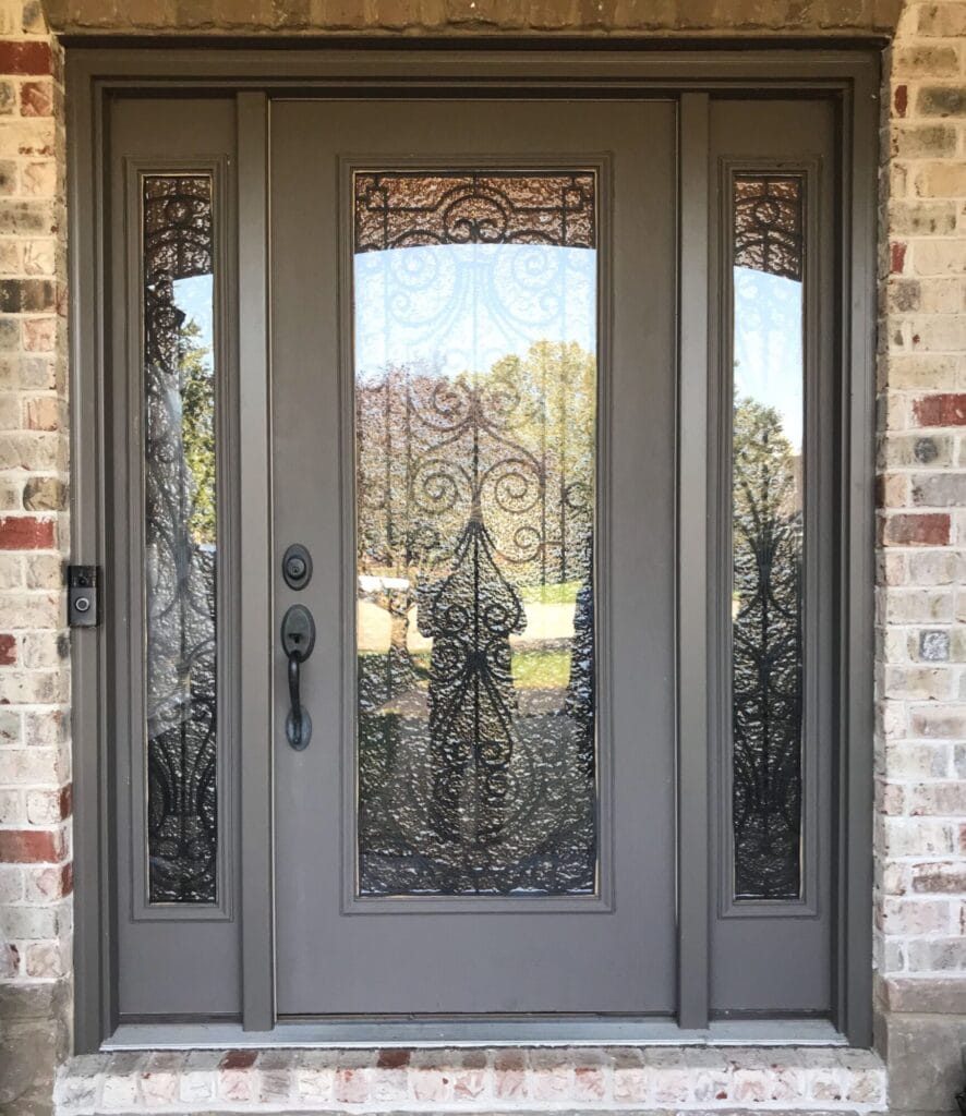 A modern gray fiberglass front door with two decorative glass side panels and an intricate wrought-iron design.