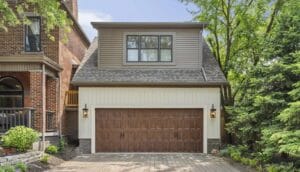 A detached garage features a wood-grain carriage door where a professional garage door panel replacement can often restore the look of a single damaged section.