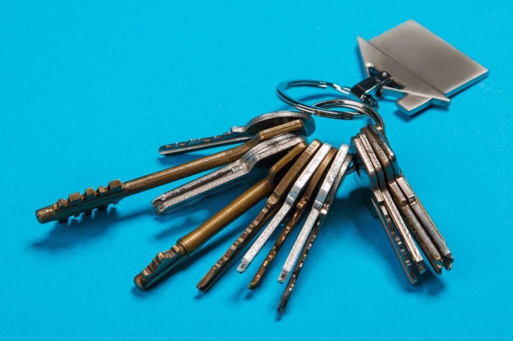 A large ring of miscellaneous silver and brass keys resting on a bright blue surface.