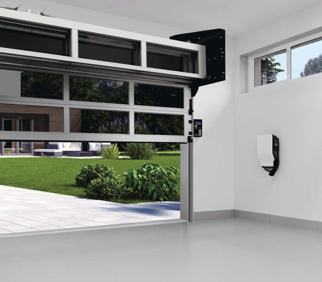 A bright interior view of a sleek modern garage featuring partially open glass garage doors with silver aluminum frames looking out onto a green backyard patio.